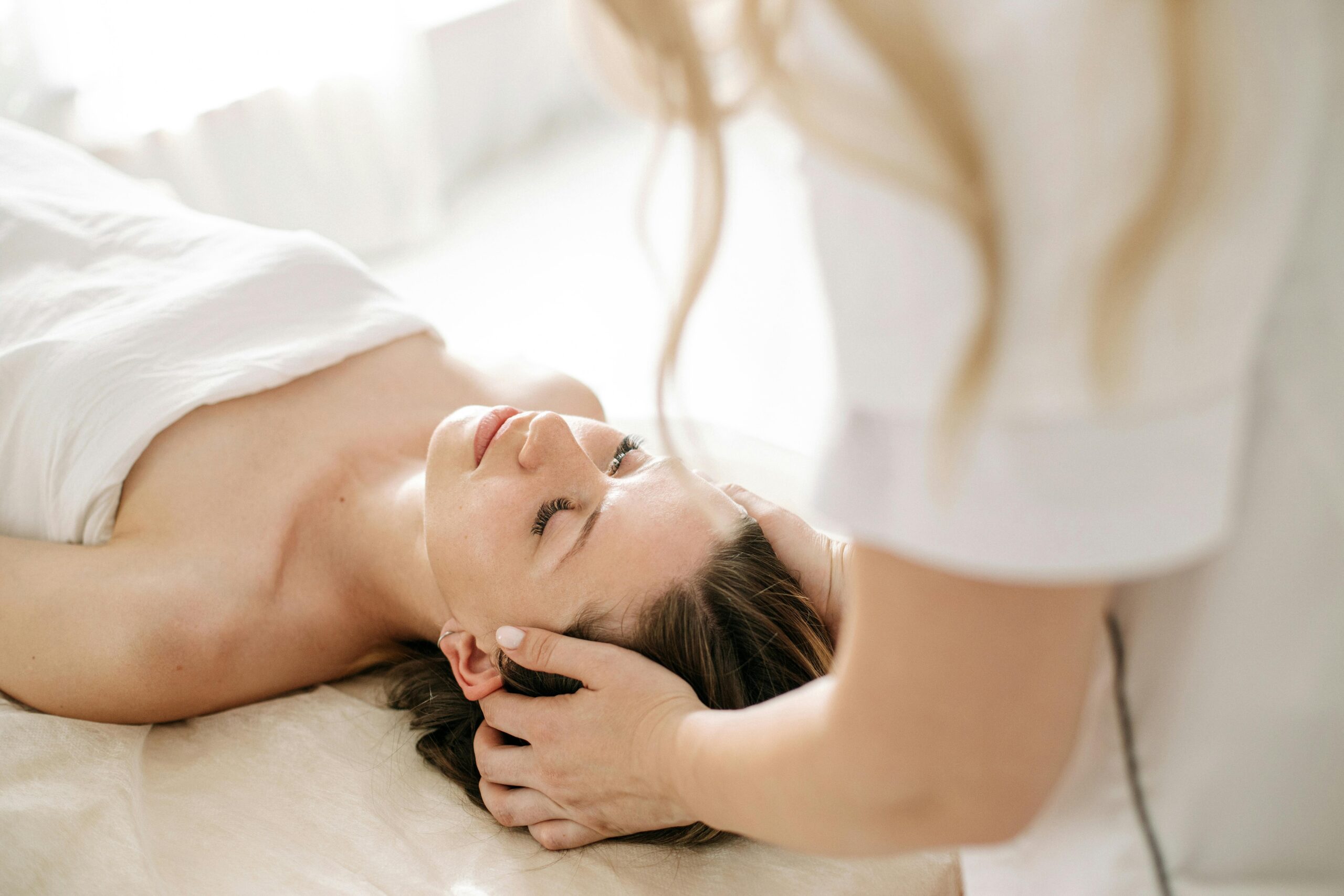 Frau erhält entspannende Kopfmassage auf Liege.