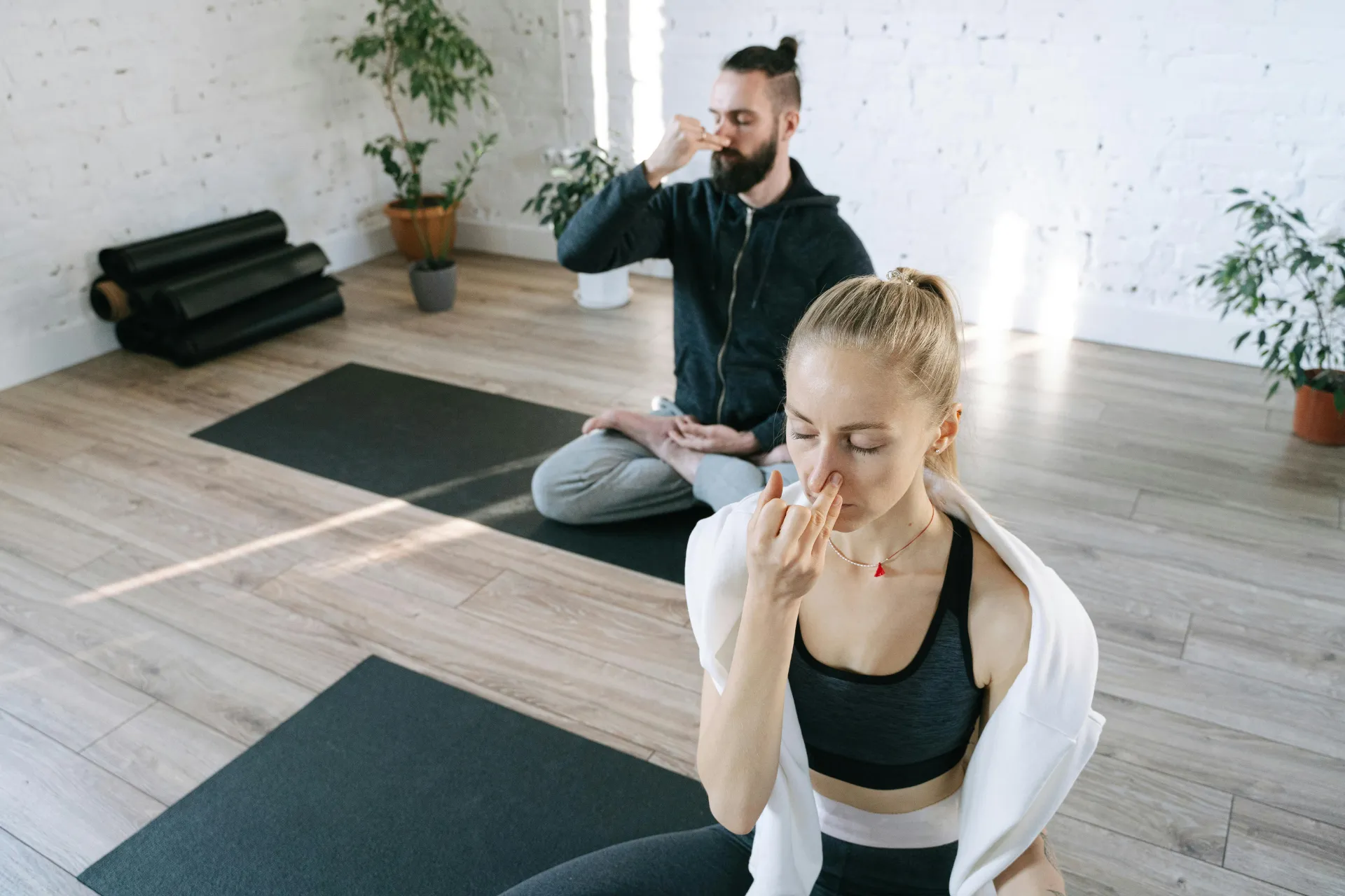 Menschen meditieren auf Yogamatten im Raum.